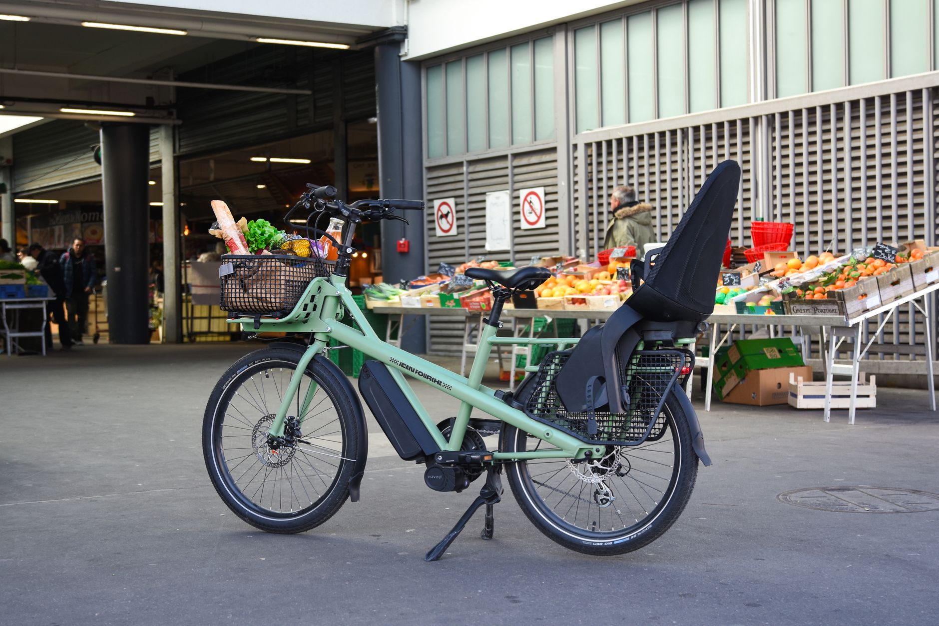 Rider with a cargo e-bike and loaded grocery bags outside a shop